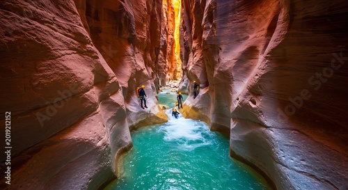 People canyoneering through a narrow slot canyon with turquoise river water and red sandstone walls