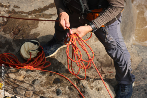 Tableau sur toile Focused climber hand holding bright orange rope checking harness knot outdoor ro