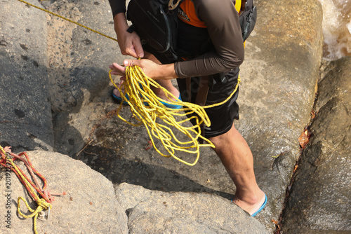 Photos Focused person holding yellow rope on rugged rock during climbing outdoor advent