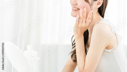 Bilde på lerret Asian woman in the mirror doing skincare (moisturizing, beauty, cosmetics, skin,