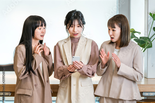 Fotografija A businesswoman boss and her subordinate are surprised when they look at a smartphone