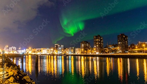 Green aurora borealis illuminating city skyline over waterfront at night