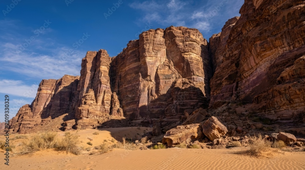 Fototapeta premium Majestic Sandstone Cliffs Under a Vast Blue Sky in Wadi Rum Desert.