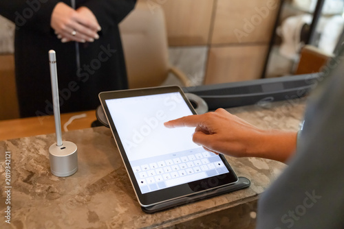 Fotografía Closeup of hotel guest using tablet for digital check-in, confirming booking details, entering information, signing form digitally at reception
