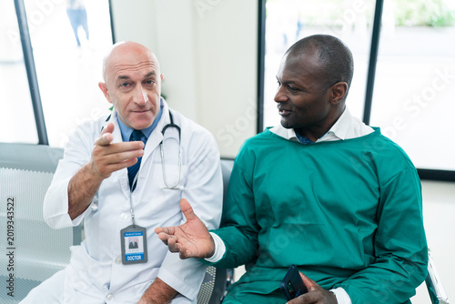 Lineated barbet bird feed nest chick doctor consultation scene shows senior physician and male surgeon talk together in modern hospital waiting area joyful teamwork and care