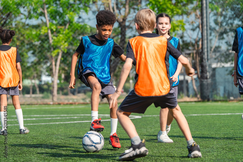 World cup concept with soccer ball or football player, youth soccer players practice on outdoor field with ball and orange and blue vest, active team sport training in sunny park