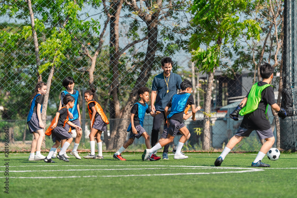 Fototapeta premium World cup concept with soccer ball or football player, youth soccer practice on outdoor field with coach and children training together