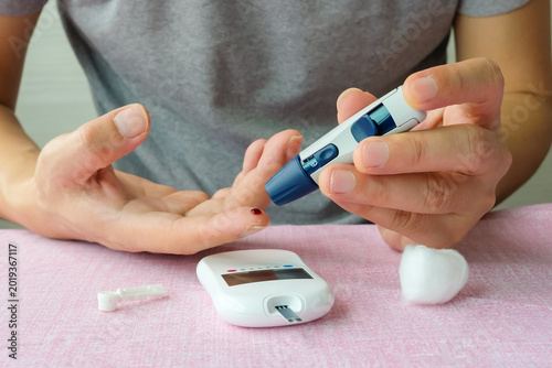 Foto Woman's hands checking diabetes and hyperglycemia with digital blood sugar meter