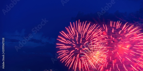 Bilde på lerret Vibrant red and pink fireworks bursting in a deep blue twilight sky