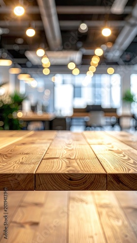 A close-up view of a warm wooden table surface with a blurred modern office interior and bokeh lights in the background.
