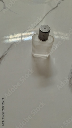 Frosted Glass Perfume Bottle with Silver Cap on White Marble Background