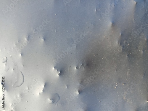 Obraz na plátně Close-up of a dented or warped light-colored surface with multiple small bumps and a prominent puncture or deep indentation