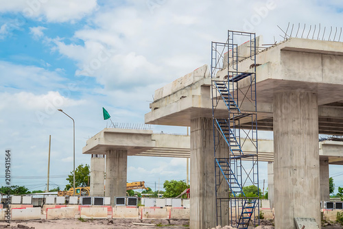 Concrete bridge under construction with scaffolding and green flag on urban site