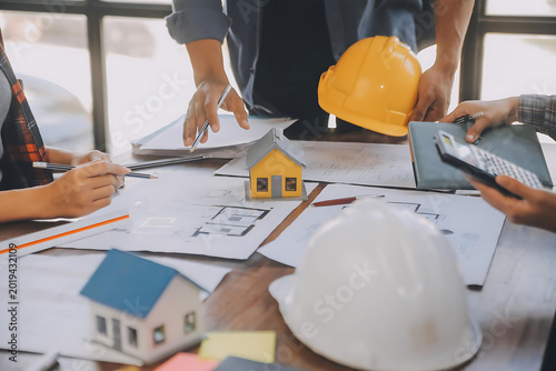 Architects reviewing house blueprints on table wearing hard hats