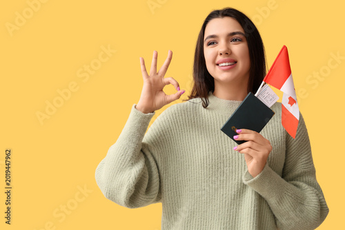 Beautiful young happy woman with Canadian flag, passport and ticket showing O...