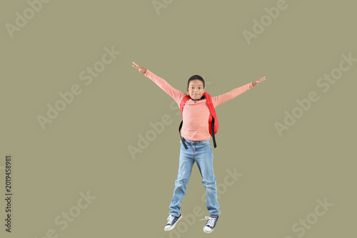Jumping African-American boy with school backpack on green background