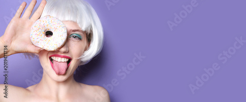 Tableau sur toile Young woman with wig and donut on color background