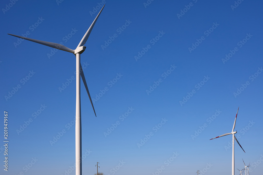 Fototapeta premium Wind turbines at sunset in green field – renewable energy, clean power, sustainable future.