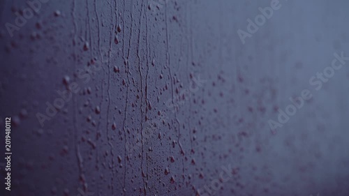 Rain drops flowing down window glass during cloudy weather