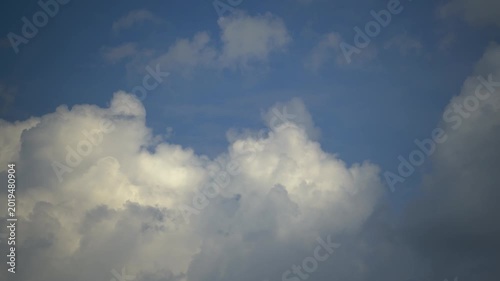 White cumulus clouds move across a blue sky on a sunny day