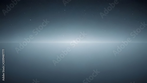 Horizon line glowing with bright light during twilight over calm water with distant stars