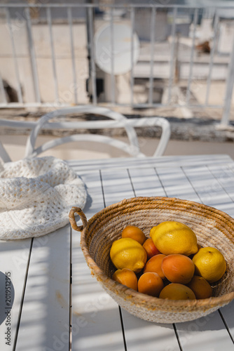 Rustic Summer Still Life Of Citrus And Stone Fruit In Straw Bowl On Mediterranean Outdoor Terrace