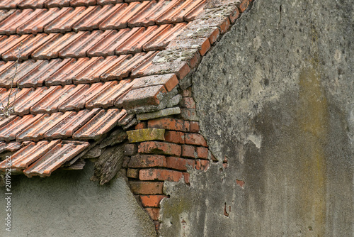 Damaged Clay Tile Roof and Weathered Wall of an Old House.