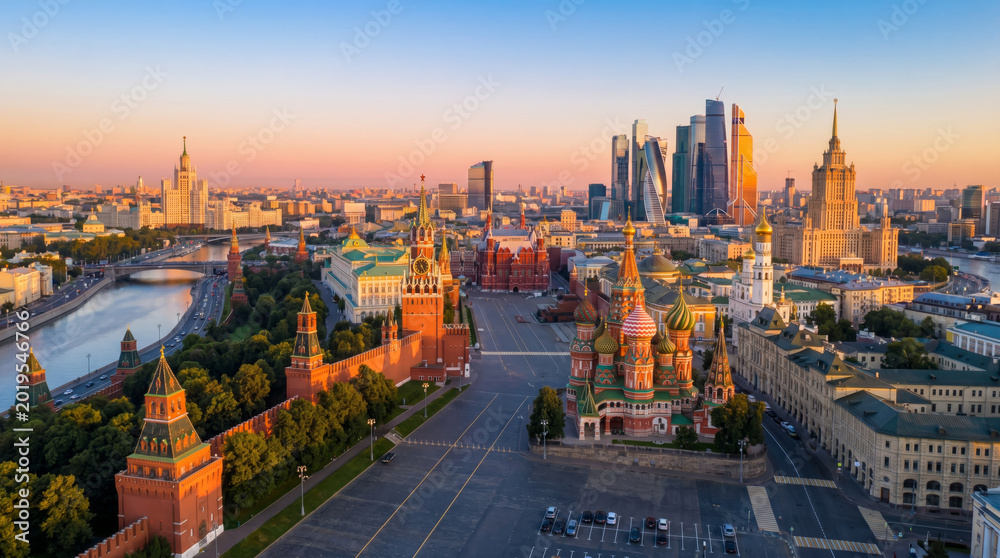 Obraz premium Panoramic view of Moscow's Red Square and Kremlin at sunrise with modern skyscrapers in the background.