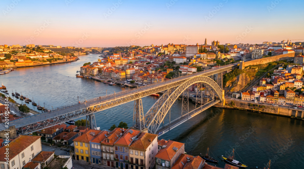 Obraz premium Aerial view of the Dom Luís I Bridge spanning the Douro River in Porto, Portugal at sunset.