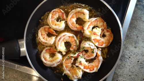 Shrimp sizzling in a hot pan, cooking in a flavorful garlic butter sauce with fresh parsley for a delicious meal