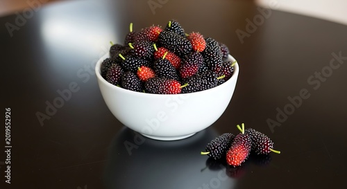 Fresh mulberries in white bowl on black surface natural light close up