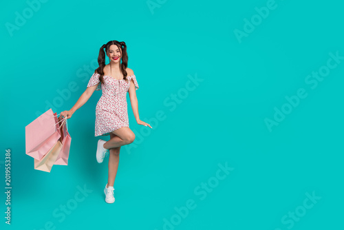 Photography Happy young woman in a pink dress with shopping bags poses against teal backgrou