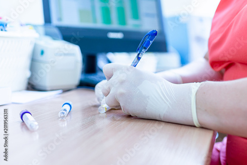 Hantavirus concept. Doctors hand writes on a blood samples in the laboratory. Close-up.