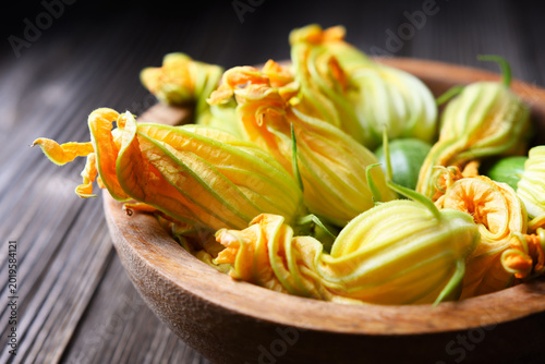 Zucchini blossoms arranged in bowl, organic edible flowers, rustic kitchen styling. Yellow squash flowers close-up, healthy seasonal produce, vegetarian ingredient