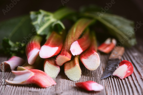 Konstfotografi Rhubarb stalks stacked on wooden table with scattered slices in foreground, shallow depth of field