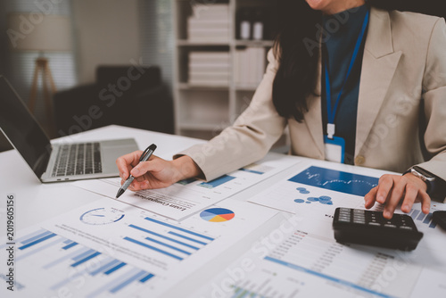 Businesswoman analyzing financial data using pen and calculator