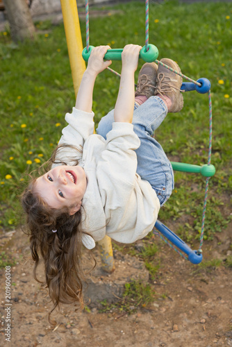 Happy Girl Hanging on Playground Ladder – Joyful Childhood, Kids Sports and Outdoor Fun
