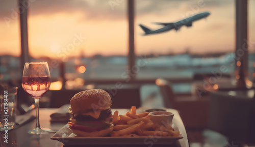Meal and wine by window with airplane takeoff at sunset