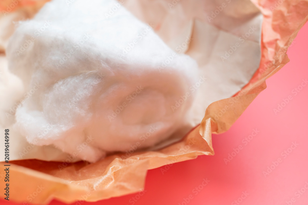 Naklejka premium Cotton wool on pink background with space for text. Medical or cosmetic natural cotton wool. Eco-friendly fiber material for personal hygiene