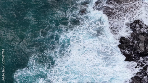 Obraz na płótnie Aerial View of Turquoise Ocean Waves Crashing Against Dark Coastal Rocks