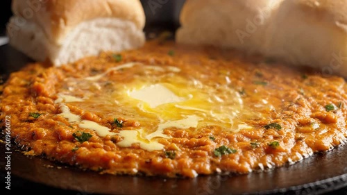 Spicy pav bhaji with melting butter and soft buns in a warm, vibrant close-up street food setting.