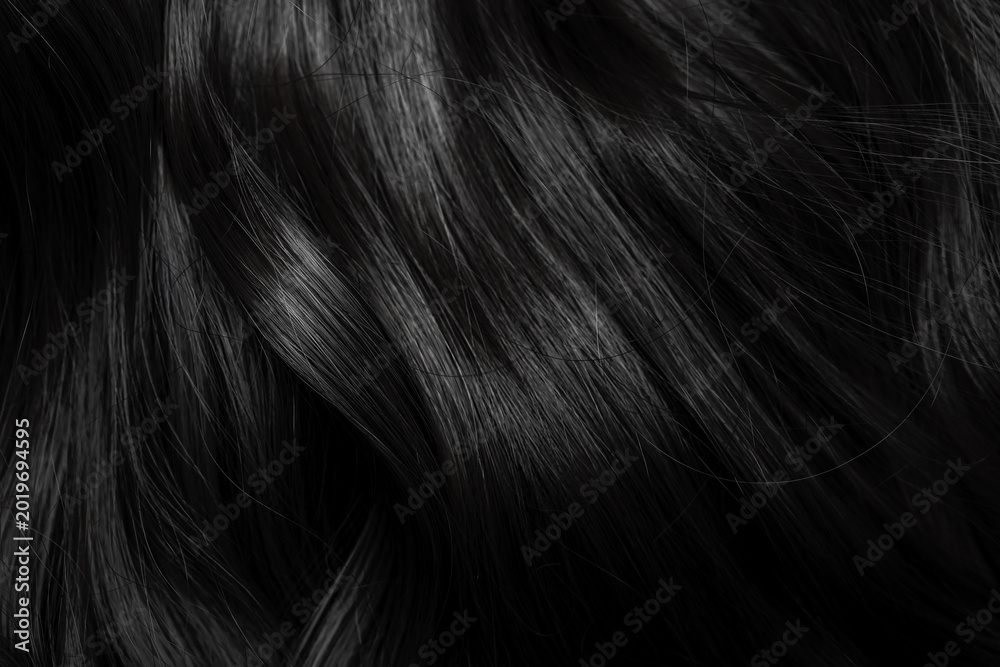 Naklejka premium Brunette or black hair. Female long dark hair in black. Beautifully laid curls. Closeup texture in a dark key. Hairdressing, hair care and coloring. Shading gray hair. Background with copy space.
