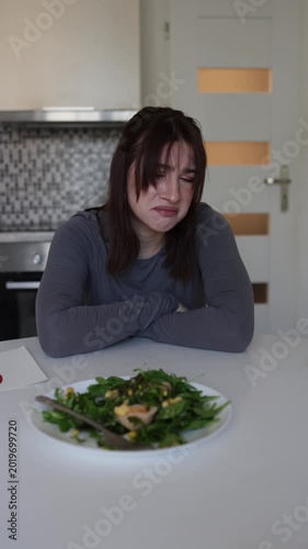 Vertical screen frustrated woman rejects healthy salad and struggles with pressure of strict dieting while feeling emotionally exhausted during unhealthy food routine