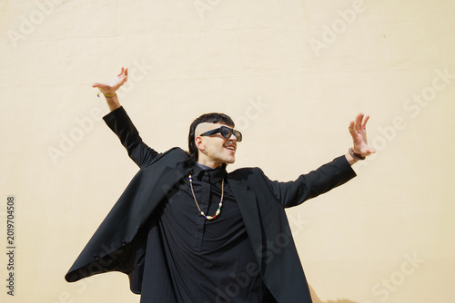 Side view of a young man dancing in front of a peach-colored wall outdoors