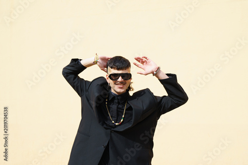 Portrait of a young man smiling and looking at the camera against a peach-colored wall outdoors