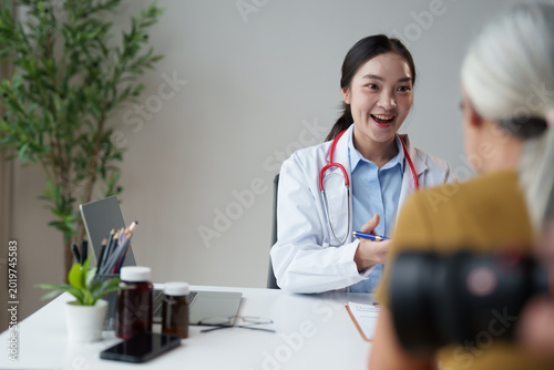 Fotografie Young female Asian doctor consulting senior patient, explaining medication dosag