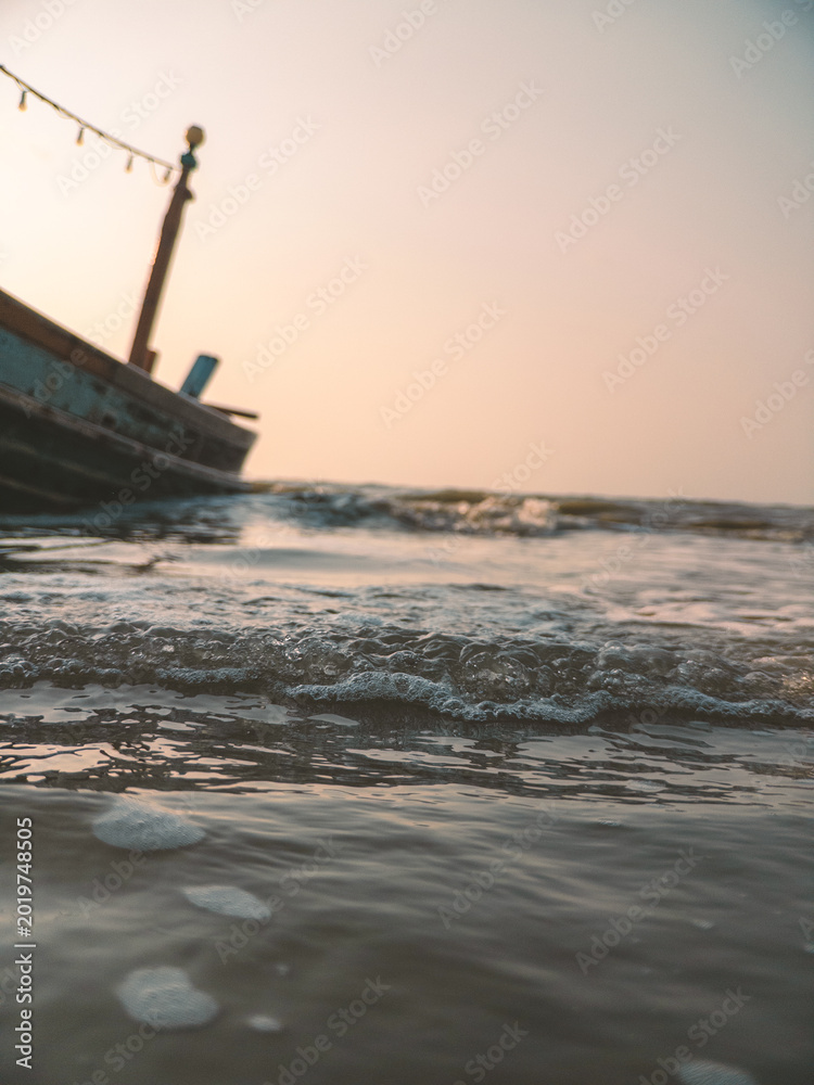 Fototapeta premium Serene shoreline capturing waves by aged pier with subdued sky