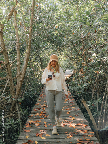 Morning walk with relaxed woman carrying drink through nature