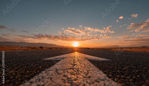 A solitary road stretches towards a vibrant sunset, creating a and inviting pathway across a textured asphalt surface