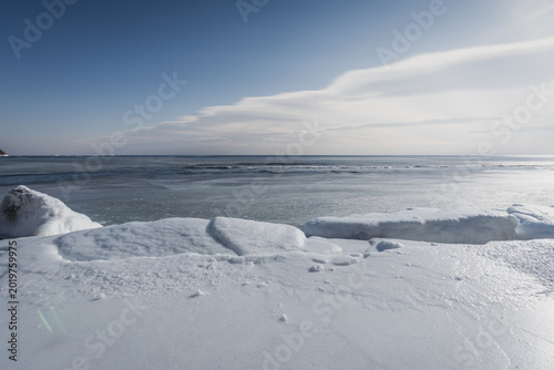 Foto Expansive view of frozen lake with snow-covered shoreline under a clear blue sky